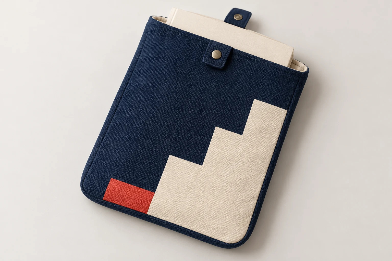Midnight-blue fabric book sleeve with cream page-step graphics, a red accent and a snap-tab opening